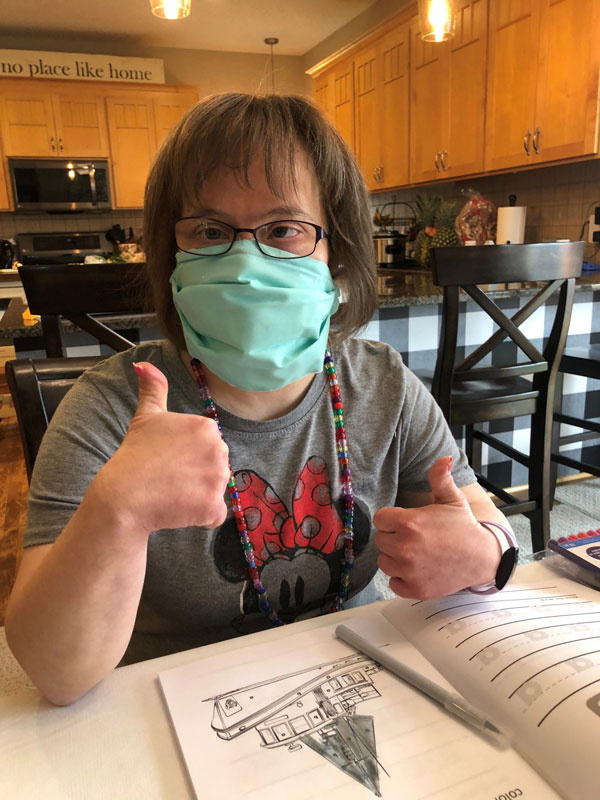 Lisa, another ProAct participant, also practices wearing her mask, and gives it a “thumbs up.”