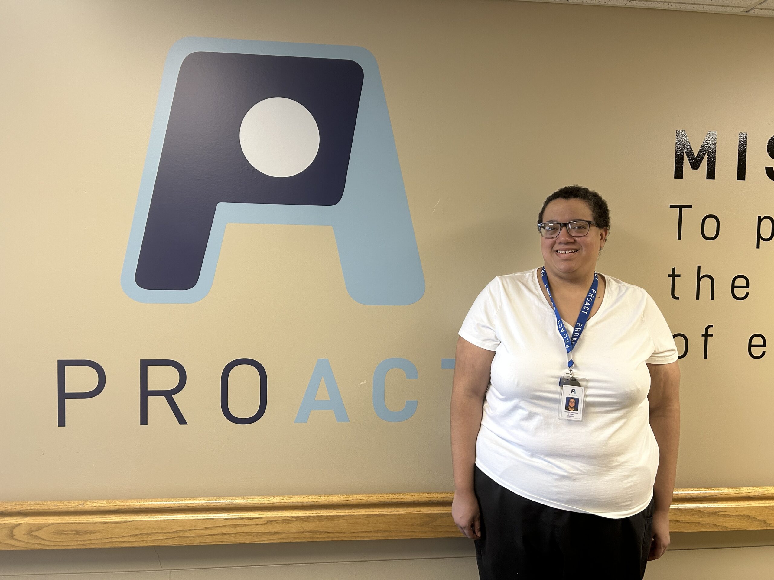 Production Assistant Millie posing in front of ProAct logo